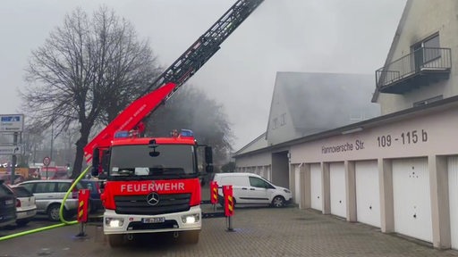 Ein Feuerwehrauto steht einem Parkplatz und löscht einen Dachstuhl.