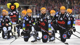 Mehrere Spieler der Fischtown Pinguins knien nach einem Sieg auf dem Eis.