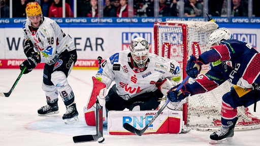 Pinguins-Torhüter Kristers Gudlevski wehrt einen Schuss eines Eisbären-Stürmers ab.