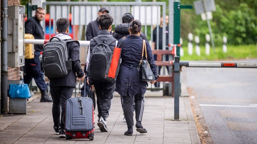 Eine Familie, vollbepackt mit Taschen und Koffern auf dem Weg durch einen Kontrollberreich.