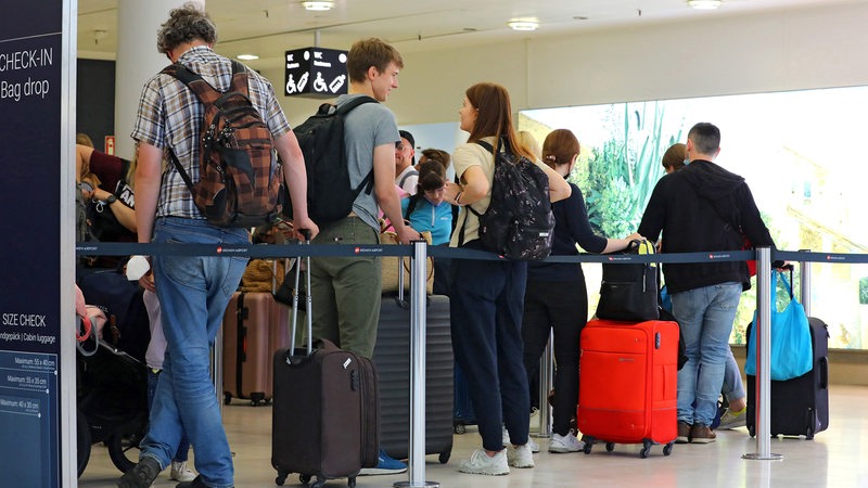 Reisende beim Check-In ihrer Koffer mit einer riesigen Warteschlange