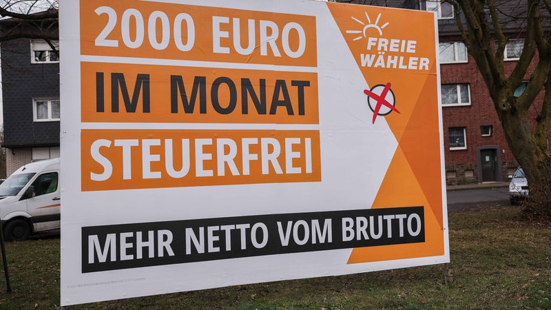 Ein Wahlplakat der Freien Wähler zur Bundestagswahl steht vor Häusern.