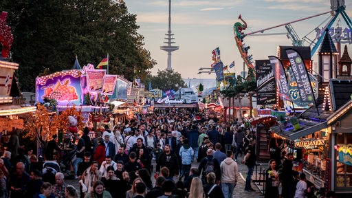 Besucher gehen zwischen Ständen und Fahrgeschäften auf dem 989. Freimarkt. 