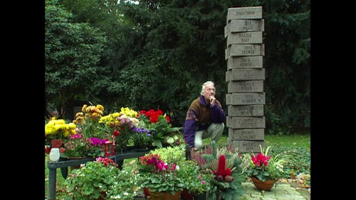 Ein Friedhof-Besucher schaut sich eine Grabsteinsammlung an.