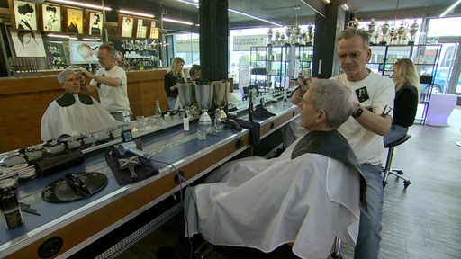 Ein Friseur schneidet einem Mann die Haare.