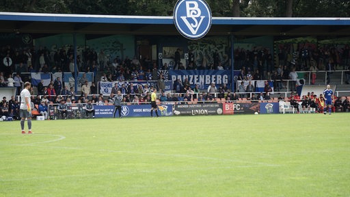 Malte Seemann steht im Tor, die Fans verfolgen das Spiel von der Tribüne.