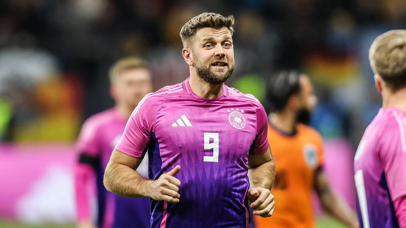 Niclas Füllkrug steht im pinken DFB-Trikot auf dem Platz.