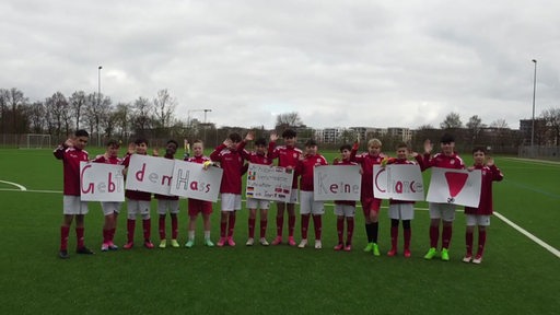 Die D-Jugend aus Woltmershausen mit Schildern auf den Botschaften gegen Hass stehen.