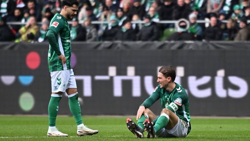 Die Werder-Fußballprofis Leonardo Bittencourt und Niklas Stark stehen und sitzen frustriert auf dem Rasen nach der Niederlage gegen Hoffenheim.