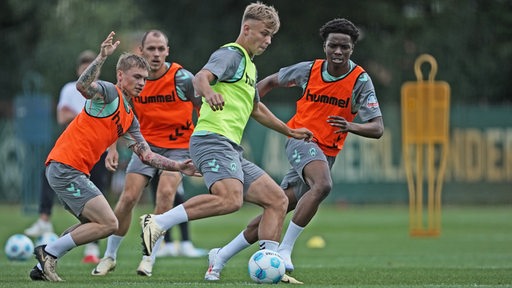 Werder-Stürmer Keke Topp hat beim Training den Ball am Fuß. Seine drei Gegenspieler versuchen, ihm den Ball abzunehmen.