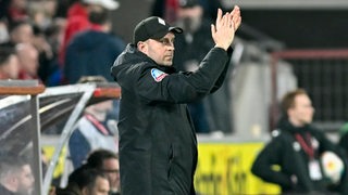 Werder-Trainer Ole Werner applaudiert seiner Mannschaft von der Seitenlinie im Kölner Stadion zu.