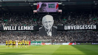 Die Fans von Werder Bremen gedenken mit einer Choreografie an den verstorbenen ehemaligen Manager Willi Lemke, die Mannschaften von Werder und Dortmund stehen dabei Arm in Arm auf dem Rasen.