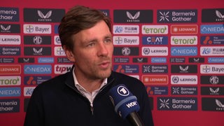 Werder-Sportchef Clemens Fritz steht nach dem Spiel in Leverkusen vor einer Werbewand beim Interview.