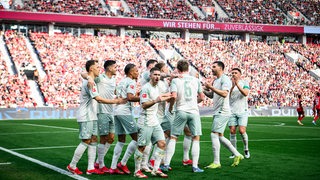 Werder-Spieler kommen im Leverkusener Stadion zusammen, um den Treffer von Romano Schmid zu feiern.