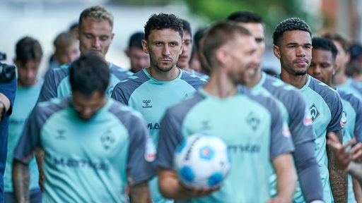 Die Werder-Spieler gehen gemeinsam den Weg zum Trainingsplatz entlang, im Fokus dabei Milos Veljkovic.