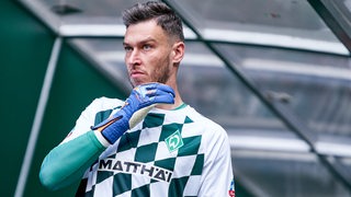 Werder-Torwart Jiri Pavlenka kommt nachdenklich zum Aufwärmen aus dem Spielertunnel des Weser-Stadions heraus und streicht sich übers Kinn.