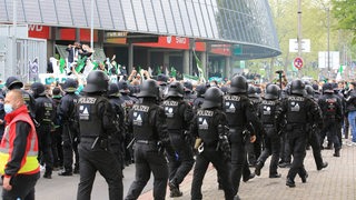 Polizeikräfte laufen behelmt vor dem Weser-Stadion entlang.