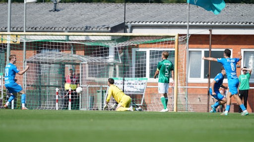 Werders U23 kassiert ein Gegentor gegen BW Lohne. Der Ball zappelt im Netz und der Torwart kann dem Ball nur hinterherschauen. Zwei Lohner Spieler jubeln.