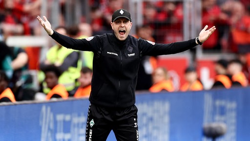 Werder-Trainer Ole Werner schreit mit weit ausgebreiteten Armen an der Seitenlinie.