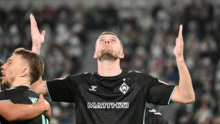 Werder-Stürmer Marvin Ducksch reckt nach seinem Tor in Wolfsburg die Arme empor und schaut gen Himmel.