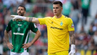 Werder-Torwart Michael Zetterer gestikuliert mit seinem rechten Arm für seine Mitspieler bei einem Freistoß.