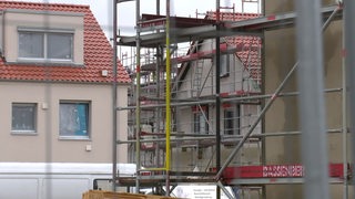 Große Baugerüste auf einer Baustelle an aneinander stehenden Häusern.