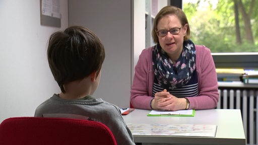 Ein Junge und eine Frau an einem Tisch bei einer Beratung