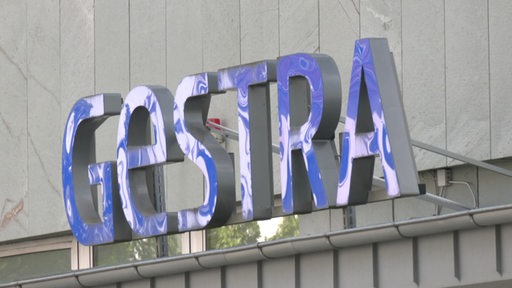 Das blaue Logo der Gestra hängt an einem Gebäude.