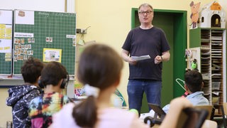 Ein Lehrer steht vor einer Grundschulklasse