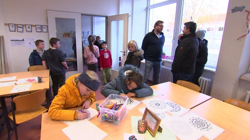 Malende Schüler sitzen am Tisch einer Schule 