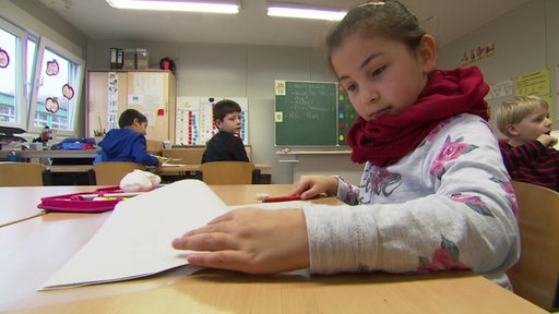 Eine Schülerin einer Grundschulklasse beim Lernen im Klassenraum.