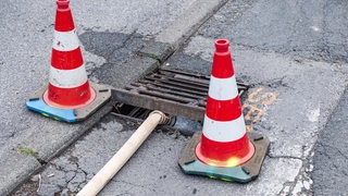 Ein Schlauch leitet Flüssigkeit in einen Gully.