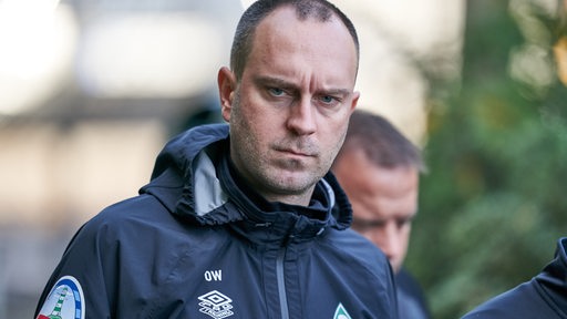 Werder-Trainer Ole Werner schaut ernst auf dem Weg zum Trainingsplatz.