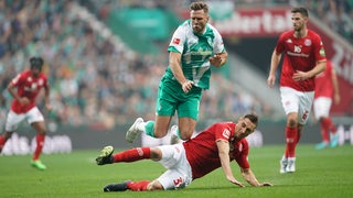 Werder-Stürmer Niclas Füllkrug fliegt nach einer Grätsche durch die Luft.