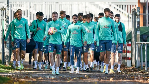 Werder-Spieler sind in der Gruppe auf dem Weg zum Trainingsplatz.