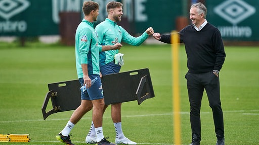 Werder-Sportchef Frank Baumann begrüßt auf dem Trainingsplatz gut gelaunt Stürmer Niclas Füllkrug.