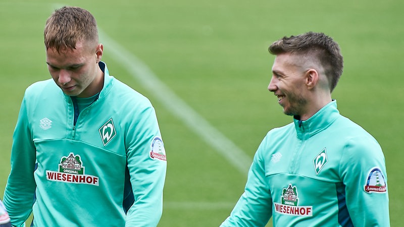 Die Werder-Spieler Niklas Schmidt und Mitchell Weiser schlendern lachend vom Platz.