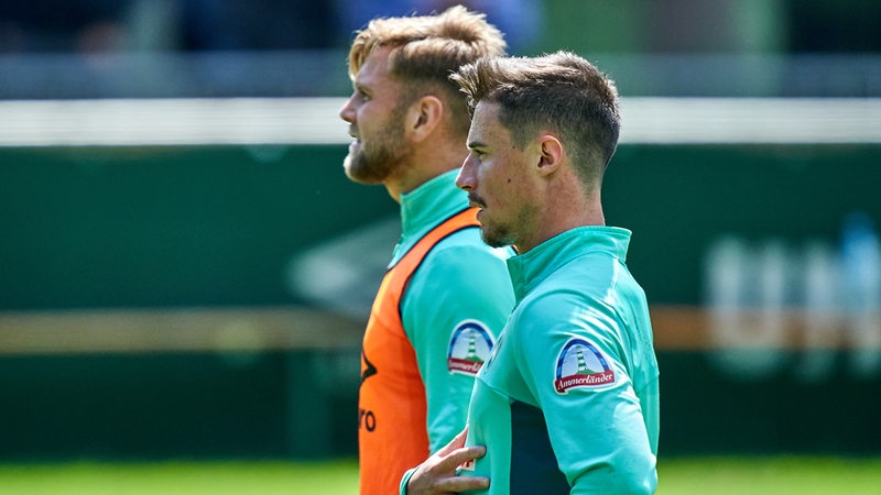 Marco Friedl und Niclas Füllkrug stehen am Rande des Werder-Trainings nebeneinander.