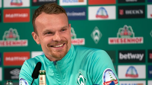 Werder-Spieler Christian Groß lächelt während einer Pressekonferenz.