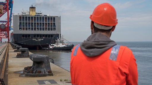 Ein Hafenarbeiter des JadeWeserPorts (JWP) in Wilhelmshaven (Niedersachsen) verfolgt das Anlegemanöver eines Containerfrachters