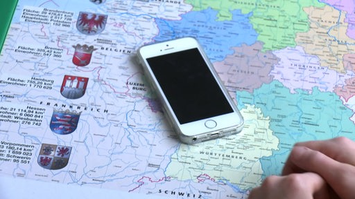 Ein ausgeschaltetes Handy liegt auf einer Landkarte der Bundesrepublik Deutschland