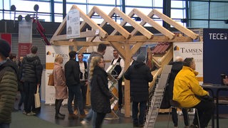 Besucher auf der Hansebau. Es sind verschiedene Stände zum Thema Hausbau zu erkennen.