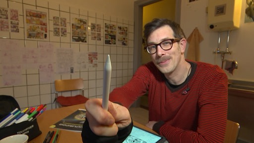 Jeff Hemmer mit einem digitalen Malstift in der Hand an seinem Arbeitsplatz.