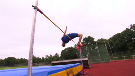 Ein Sportler springt rückwärts über eine Hochsprungstange