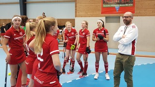 BHC-Trainer Florian Keller beim ersten Training umringt von seinen Spielerinnen in der Halle.