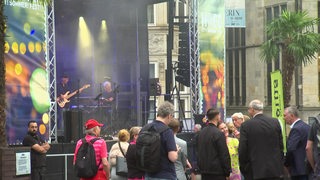 Bei einem Konzert beim Hoeg CitySommerFest stehen mehrere Menschen auf dem Domshof vor einer Bühne.