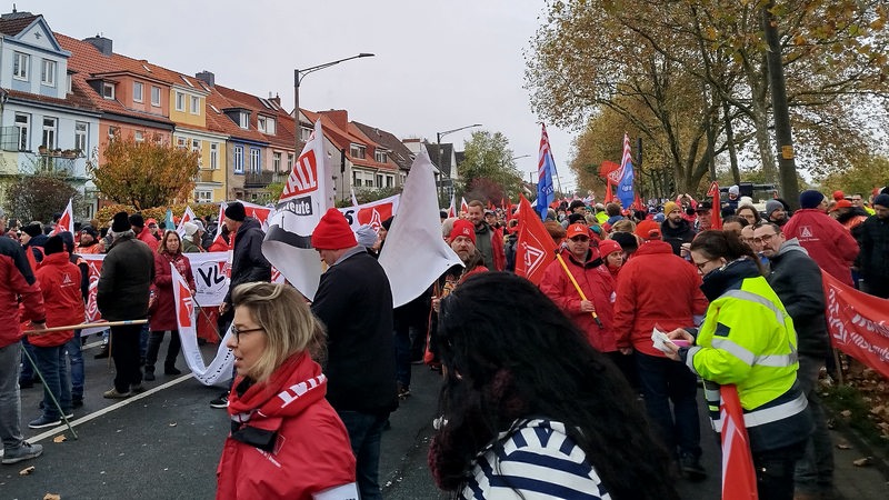 Eine Menschenmenge in größtenteils roten Jacken demonstriert auf einer Straße.