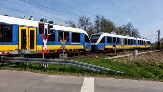 Ein Zug der Nordwestbahn durchfährt einen beschrankten Bahnübergang 