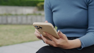 Eine Frau hält ein Smartphone in den Händen.