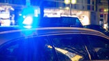 Ein Polizeiauto mit Blaulicht steht vor einem Gebäude.